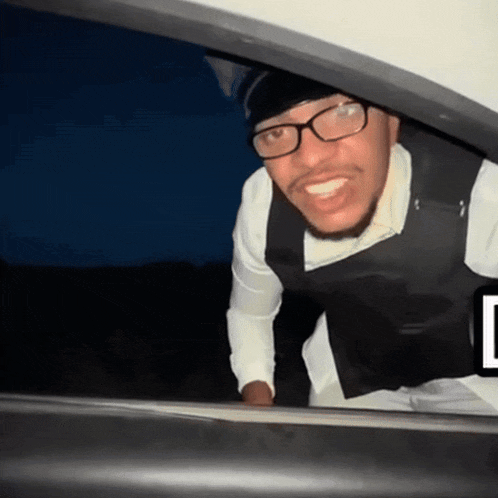 a man wearing glasses and a bullet proof vest is looking out of a car window