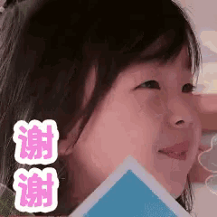 a little girl is holding a piece of paper in front of her face and smiling .