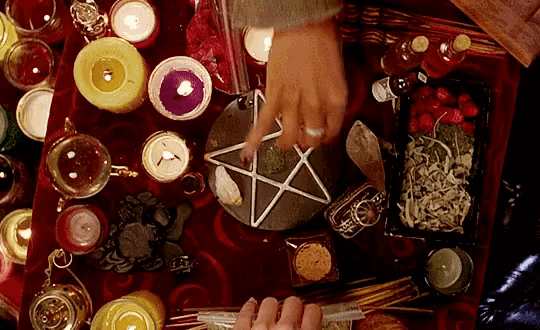 a person is making a pentagram on a table surrounded by candles and crystals