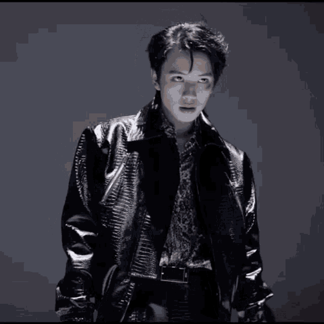 a young man in a black leather jacket and leopard print shirt