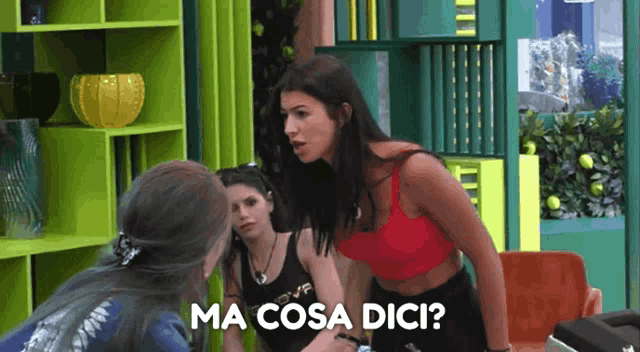 a woman in a red top is talking to another woman and the words ma cosa dici are visible