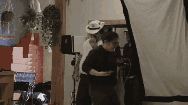 a man in a cowboy hat is talking to another man in a black shirt