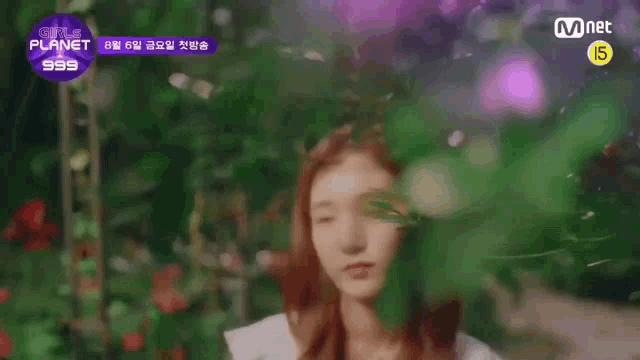 a girl with red hair is standing in front of a purple background with flowers .
