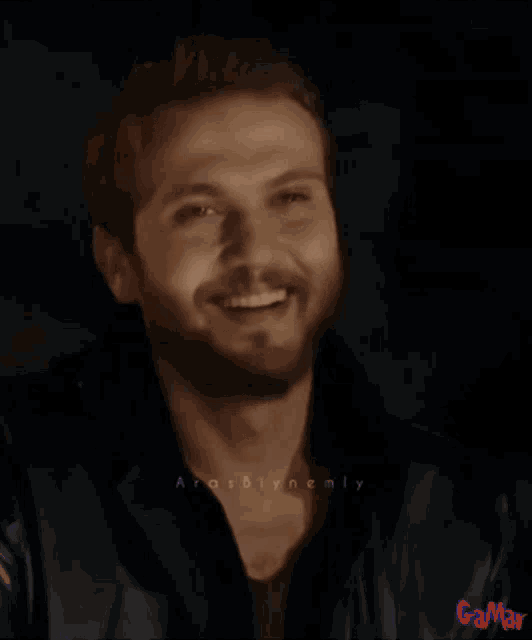a man with a beard is smiling and the word güzel is displayed above him
