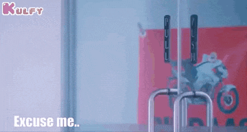 a person is standing in front of a glass door with a motorcycle in the background and says `` excuse me '' .