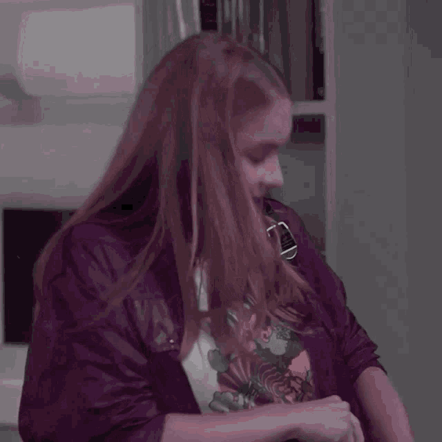 a woman with long red hair wearing a purple jacket