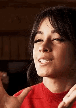 a close up of a woman wearing a red sweater making a face .