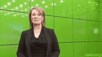 a woman is standing in front of a green wall and making a funny face .