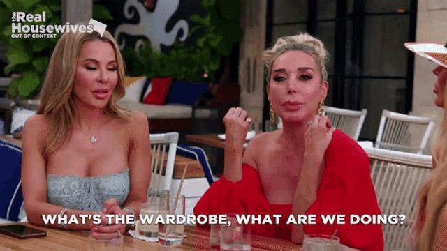 two women sitting at a table with the words " what 's the wardrobe what are we doing " on the screen