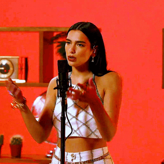 a woman singing into a microphone in front of a red background