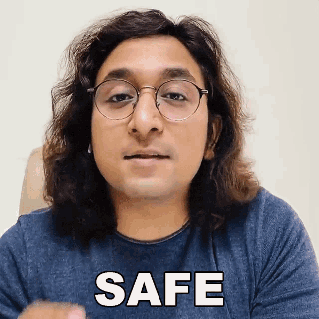 a man with long hair wearing glasses and a blue shirt that says safe