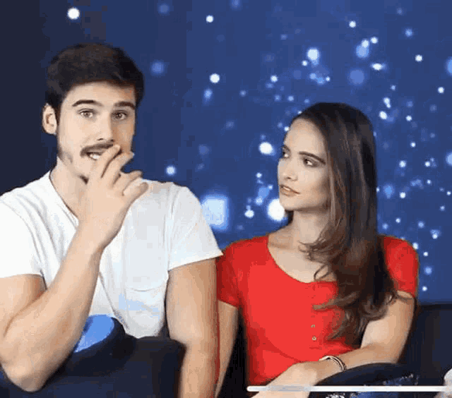 a man and a woman are sitting next to each other and the woman is wearing a red top
