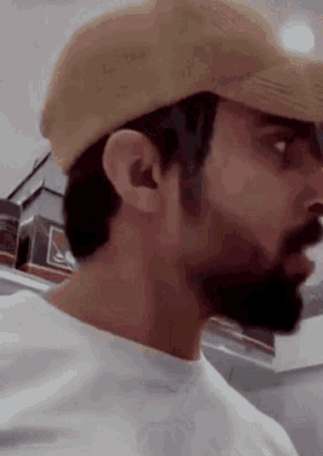 a man with a beard wearing a baseball cap and a white shirt