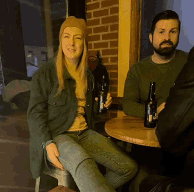 a man and a woman sit at a table holding bottles