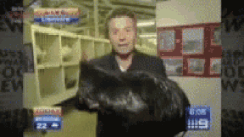a man is holding a large black object in front of a sign that says ' abc news ' on it