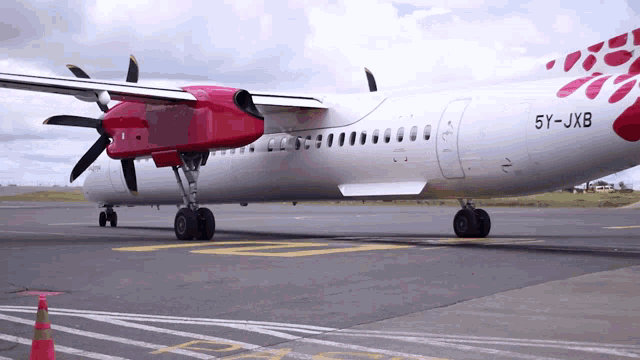 a red and white airplane with the number 5y-jxb on the side