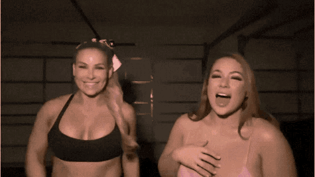 two women are waving their hands in a dark room