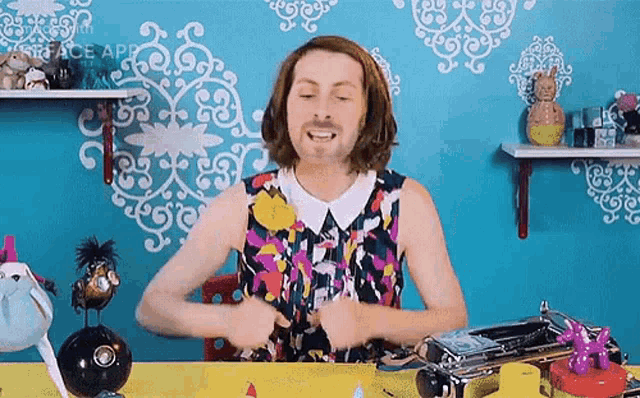a man in a colorful dress is sitting at a table with a typewriter in front of him .