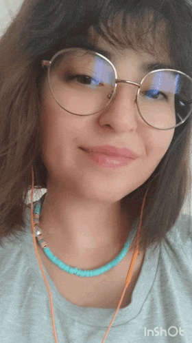 a woman wearing glasses and a turquoise necklace smiles