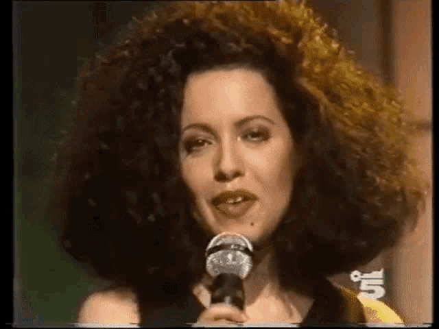 a woman with a large afro is singing into a microphone .