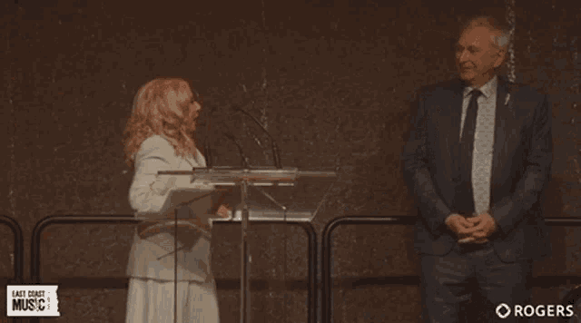 a man and a woman are dancing in front of a podium that says east coast music on it