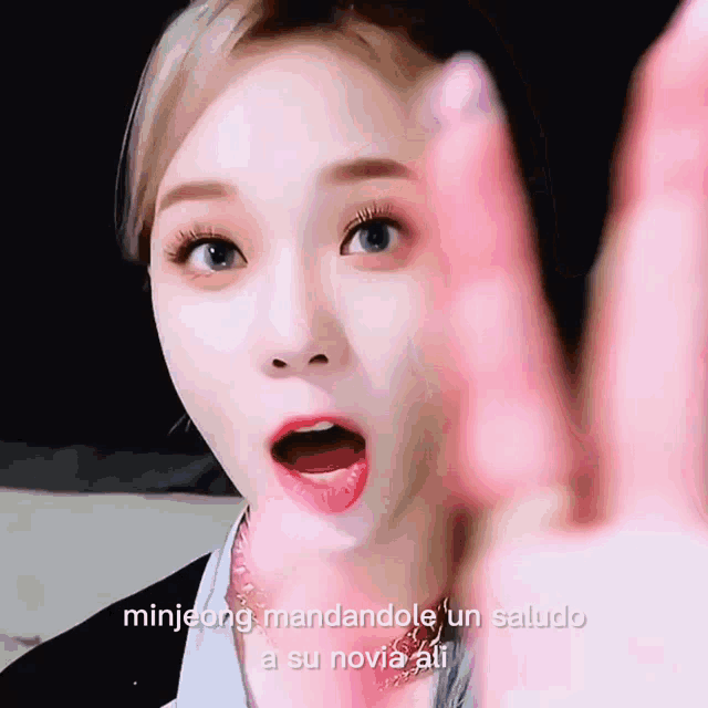 a close up of a woman 's face with the words minijeong mandandole un saludo a su novia ali written below her