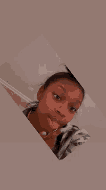 a young girl is taking a selfie with a lollipop in her hand .