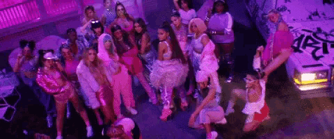 ariana grande is surrounded by a large group of women in pink clothes .