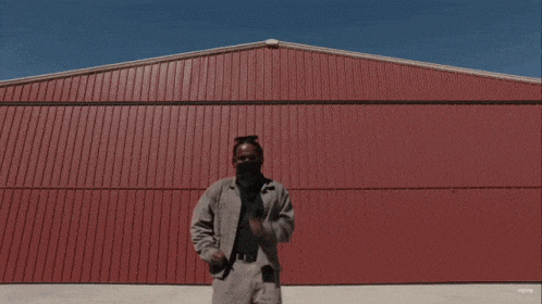 a man is standing in front of a red building that says ' youtube ' on it