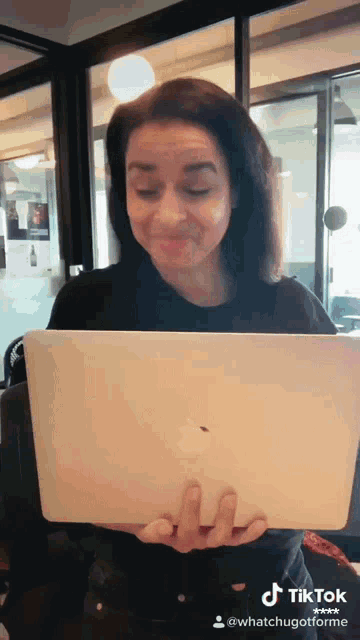 a woman is holding an apple laptop with a tiktok watermark on the bottom