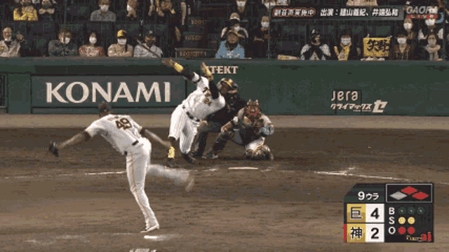 a baseball game is being played in front of a konami ad