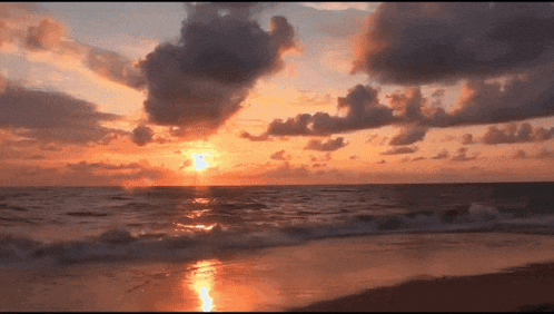 a sunset over the ocean with a few clouds