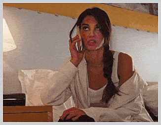 a woman sitting on a bed talking on a cellphone