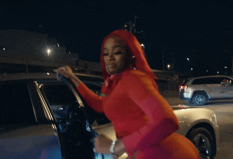 a woman in a red dress is getting out of a silver car