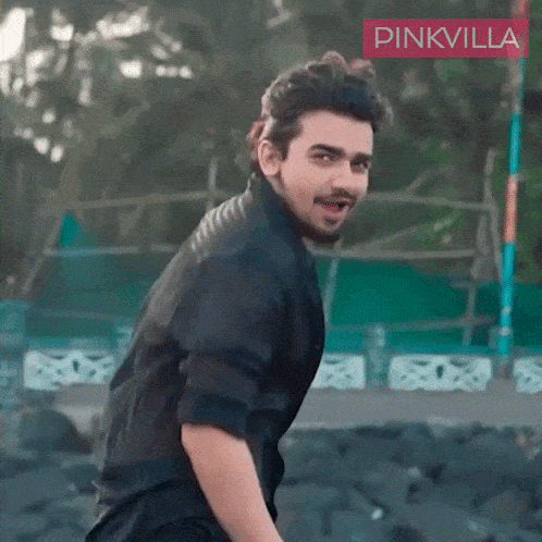 a man in a black shirt is smiling in front of a pinkvilla logo
