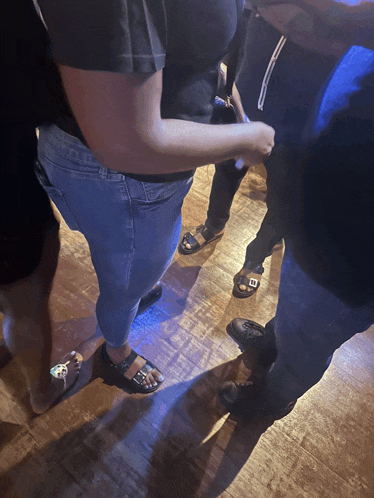 a group of people are standing on a wooden floor with one wearing a black shirt with the letter e on it