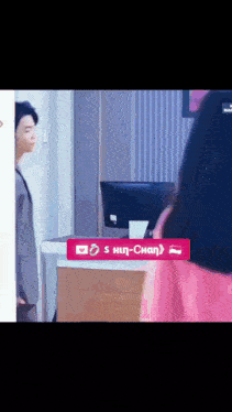 a man and a woman are standing in front of a computer and a sign that says ' s hun-chan ' on it