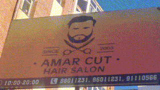 a sign for amar cut hair salon has a red arrow pointing to the right