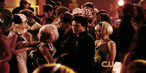 a crowd of people are gathered in a room with a cw logo in the background