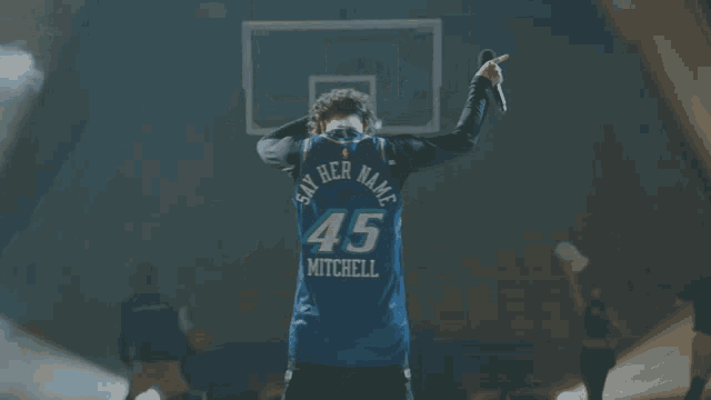 a man in a 45 mitchell jersey stands in front of a basketball net