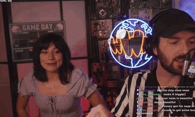 a man and a woman are standing in front of a neon sign that says " game day "