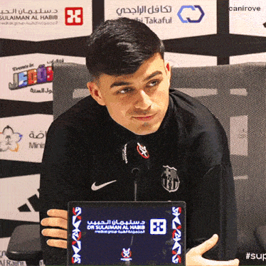 a man holding a tablet that says dr sulaiman al habib on the screen