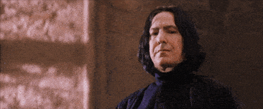 a man with long black hair is wearing a black sweater
