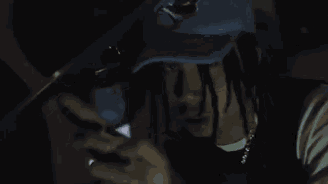 a man with dreadlocks is sitting in a car holding a cell phone .