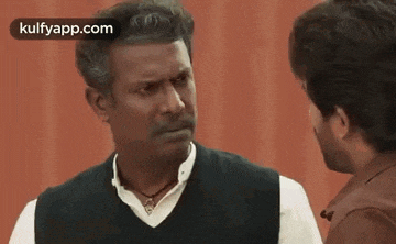 two men are talking to each other and looking at each other .