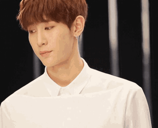a young man wearing a white shirt and earrings