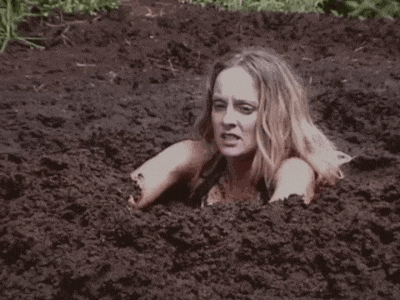 a woman is buried in a pile of mud .