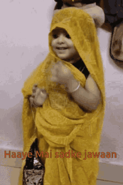 a little girl wearing a yellow saree with the words haaye mai sadke jawaan written on the bottom