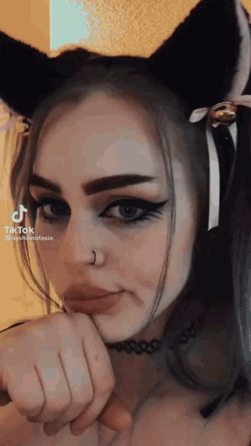 a woman wearing cat ears and a choker is making a face