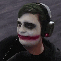 a man is wearing headphones and making a joker face while talking into a microphone .